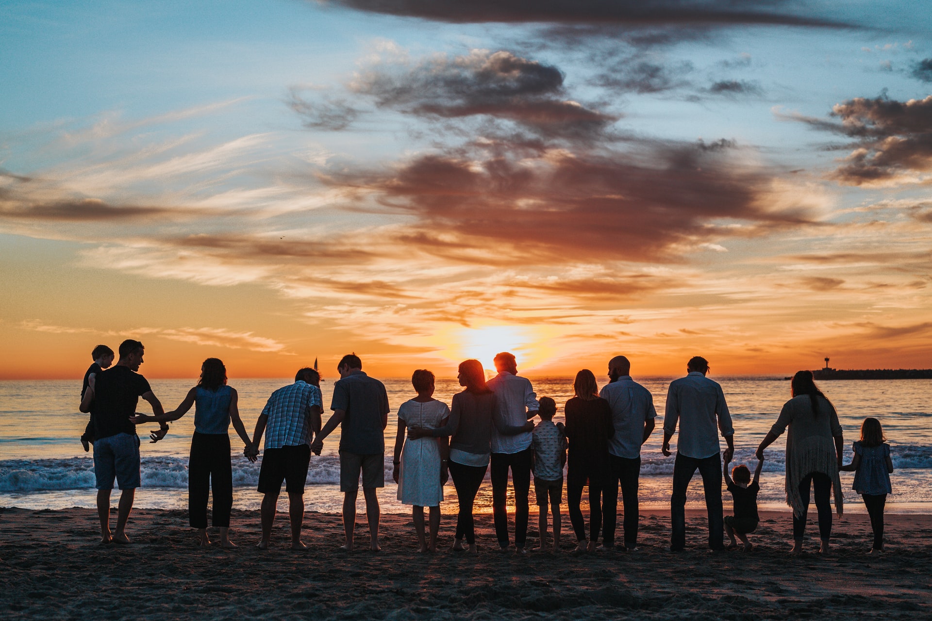 family standing on beach at sunset