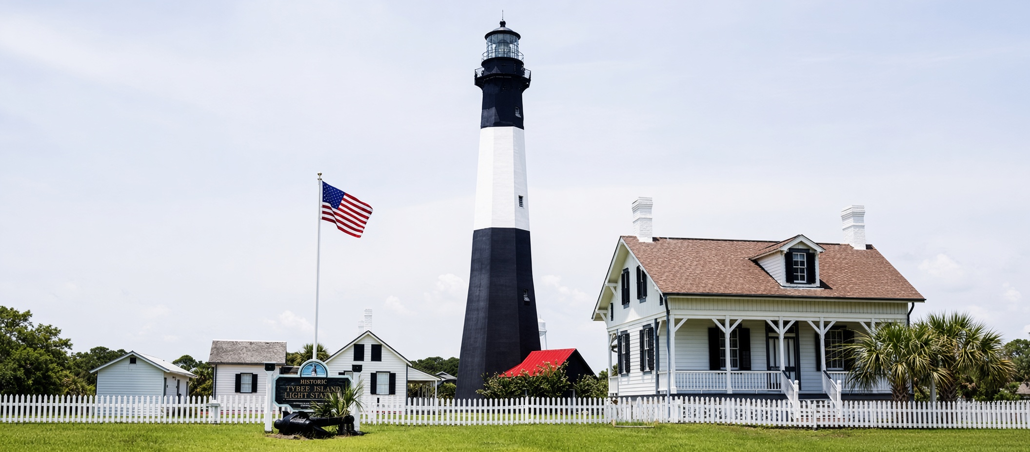 Historic black-and-white Tybee Island Lighthouse with keeper's cottage and American flag in Georgia